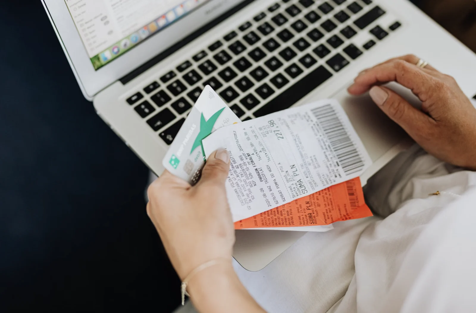 A traveler reviewing payment details and travel receipts beside a laptop.